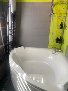eine weiße Badewanne in einem Badezimmer mit einer gelben Dusche in der Unterkunft Maison proche Nancy Golf, Forêt & Calme à Pulnoy in Pulnoy + 30 Fotos