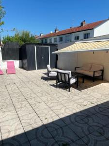 eine Terrasse mit zwei Bänken und einem großen Sonnenschirm in der Unterkunft Maison proche Nancy Golf, Forêt & Calme à Pulnoy in Pulnoy