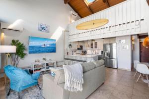 een woonkamer met een bank en een surfplank aan de muur bij Perch - Alii Kai Loft in Kihei
