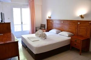 a bedroom with a large bed with a wooden headboard at Galini Hotel in Agia Marina Aegina