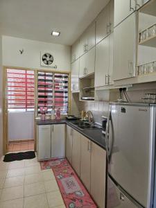 Una cocina con gabinetes blancos y un refrigerador de acero inoxidable. en Rosy Retreat, en Tambun