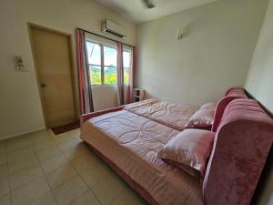 1 dormitorio con cama con sábanas rosas y ventana en Rosy Retreat, en Tambun