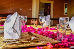 einen Tisch mit Weingläsern und rosa Blumen darauf in der Unterkunft Pembeni Rhotia in Karatu