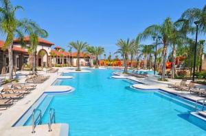 a swimming pool at a resort with chairs and palm trees at Luxurious Townhome in Solterra Resort - SOLT01 in Davenport
