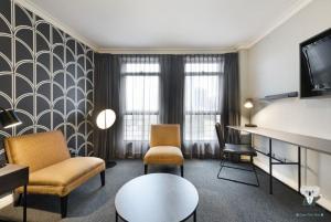 Una sala de estar con un sofá y sillas y un televisor. en KozyGuru | Sydney CBD | Best Location Studio, en Sídney