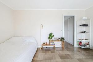 a white bedroom with a bed and a table at Charming quiet apartment near Disney in Fontenay-sous-Bois