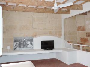 a living room with a tv and a stone wall at Andrones in Ciutadella