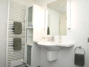 a white bathroom with a sink and a mirror at Haus Sonnenhaken Wohnung 1 in Norderney +16 photos
