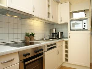 a kitchen with white cabinets and a sink and a microwave at Haus Sonnenhaken Wohnung 1 in Norderney