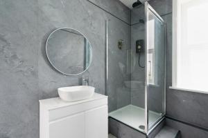 a bathroom with a sink and a shower with a mirror at Citysteps Hotels Newcastle West in Newcastle upon Tyne