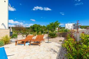 two wooden benches sitting on a stone patio at Kuća Koza-Apartment Marijana in Punat