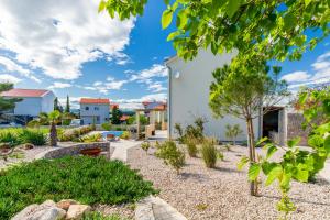 a view of a garden with a house at Kuća Koza-Apartment Marijana in Punat
