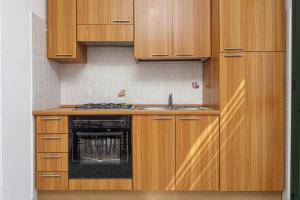a kitchen with wooden cabinets and a black dishwasher at Limpiddu in Limpiddu