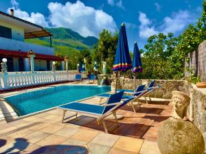 a pool with lounge chairs and umbrellas on a patio at Hotel Villa Fiorentina in Casamicciola Terme