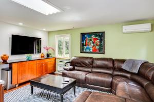 a living room with a leather couch and a flat screen tv at Charming Unit with Deck about 3 Mi to Lake Washington! in Newcastle