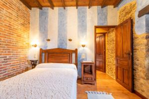 a bedroom with a bed and a brick wall at La Casona del Cura 3, CALÉNDULA in Pravia