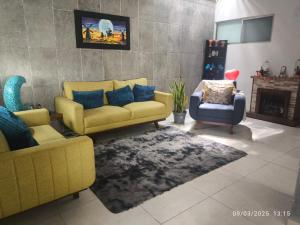 a living room with a yellow couch and a chair at Casa Montiel in Mérida