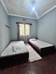 two beds in a room with a window at Bush and Forest Safari Retreat in Arusha