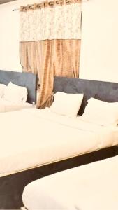 a bedroom with two beds and a window with a curtain at Hotel shiva home in Banāras Cantonment