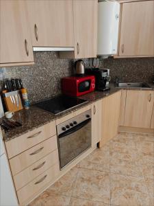 a kitchen with wooden cabinets and a red microwave at Seawolf Apartment, Lloret de Mar in Lloret de Mar