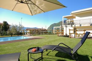 a patio with a table and a chair and an umbrella at Costa blu - terrace overlooking the lake & pool in Riva di Solto