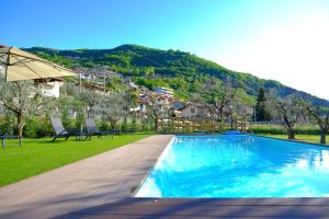 a swimming pool with two chairs and an umbrella at Costa blu - terrace overlooking the lake & pool in Riva di Solto