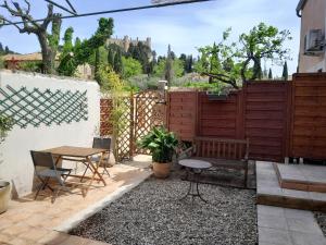 a patio with a table and a bench and a fence at Sous le tilleul in Montfaucon