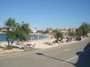 a group of people sitting on the beach near the water at Apartments Žitna Sun in Vir