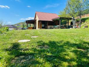 a house in a field with a grassy yard at Log cabin in Sejdanovići
