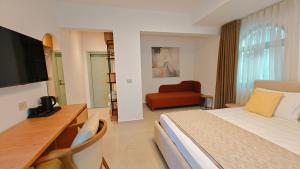 a hotel room with a bed and a desk and a chair at VILLA MARGARIT Boutique Hotel in Sarandë