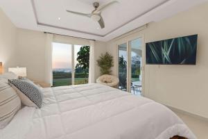 a white bedroom with a large bed and a ceiling fan at Infinity Pools & Sunsets Over Tamarindo Bay in Tamarindo