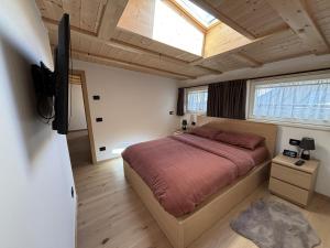 Un dormitorio con una cama y un televisor. en Appartamento Cima 12, en Pozza di Fassa