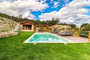 a backyard with a swimming pool and green grass at Casa Vale do Luar in Celorico de Basto