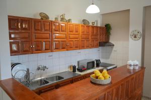 a kitchen with wooden cabinets and a bowl of fruit on a counter at Sunny apartment in Mythimna