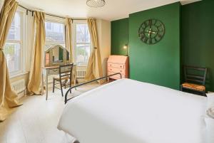 Un dormitorio con una pared verde con un reloj y un escritorio. en Host & Stay - Blatchington Road, en Brighton & Hove
