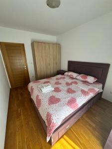 Schlafzimmer mit einem Bett mit einer roten und weißen Bettdecke in der Unterkunft City Apartment in Podgorica