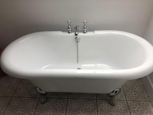 a white bath tub sitting in a room at Caretakers Hideaway in Puncknowle +16 photos