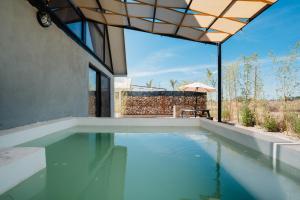 a swimming pool in a house with an umbrella at La Campiña Glamping Club in Aguascalientes