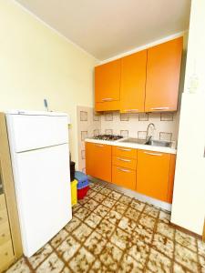 eine Küche mit orangefarbenen Schränken und einem weißen Kühlschrank in der Unterkunft Dimora Scacciapensieri a Marina di Cecina by Zoom In Earth in Marina di Cecina