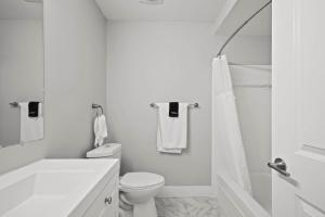 a white bathroom with a toilet and a shower at Spacious & Stylish Stay in Rochester Prime Spot in Rochester Hills