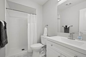 a white bathroom with a toilet and a sink at Spacious & Stylish Stay in Rochester Prime Spot in Rochester Hills