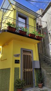 a yellow house with potted plants on a balcony at Casa vacanze Dimora Castello 19 in Rotonda