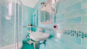 a blue tiled bathroom with a sink and a mirror at House Rene in Agerola