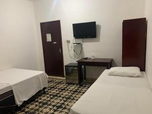 a room with two beds and a desk and a tv at Salette Hotel in Corumbá +9 photos