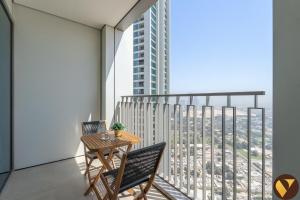 - un balcon avec une table, deux chaises et un ordinateur portable dans l'établissement DOWNTOWN VIEWS II - VOGUE One Bedroom Apartment with Balcony, 42nd Floor Opposite Dubai Mall Skybridge, à Sabkhah