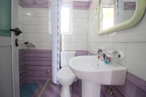 Un baño con lavabo, inodoro y espejo. en Ladin's House, en Sarandë 7 fotos más