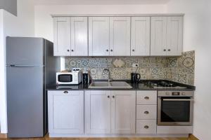 a kitchen with white cabinets and a white refrigerator at Appartamento La Ginestra - Affitti Brevi Italia in Tertenìa