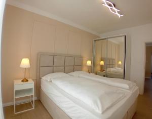 a white bedroom with a large bed and a mirror at Apartments Angie in Zadar