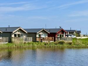 a row of houses next to a body of water at Low Lake Lodge - Lakeside - Part of the The Bay Filey Holiday Village with pool, gym and direct beach access, pub, restaurant, tennis and meadows walks in Reighton
