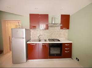 a kitchen with red cabinets and a white refrigerator at La Casetta di Coco in Bisceglie